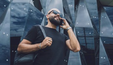 Modadan bir gencin portresi telefonda konuşuyor. Güzel, karanlık şehir arka planında.