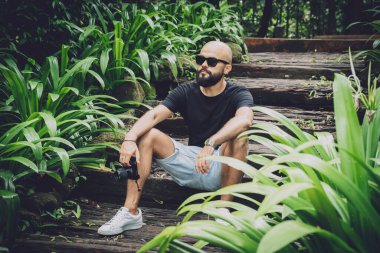 Ormanda yeşil yaprakları olan genç bir adamın portresi.