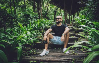 Ormanda yeşil yaprakları olan genç bir adamın portresi.