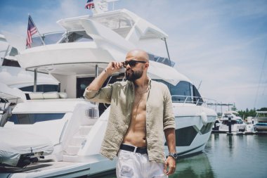 Portrait of a fashion young man posing at marina and yahts background