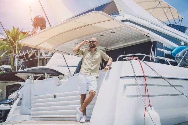 Portrait of a fashion young man posing at marina and yahts background — Foto Stock