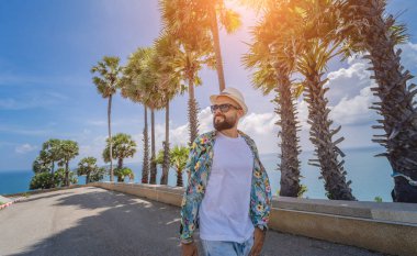 Yaz tatilinde arka planda güzel palmiyeler ve deniz manzaraları olan genç bir gezgin.
