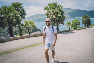 Yaz tatilinde arka planda güzel palmiyeler ve deniz manzaraları olan genç bir gezgin.