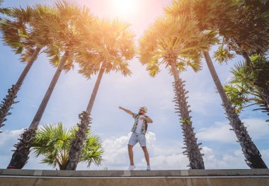 Yaz tatilinde arka planda güzel palmiyeler ve deniz manzaraları olan genç bir gezgin.