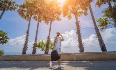 Yaz tatilinde arka planda güzel palmiyeler ve deniz manzaraları olan genç bir gezgin.