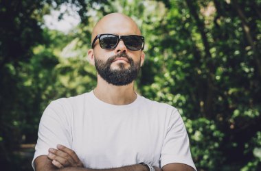 Şık bir genç adam ve motosikleti ormanda yolda.