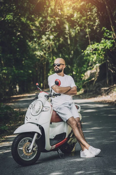 Stílusos fiatalember és motorja az úton a dzsungelben — Stock Fotó