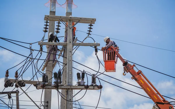 Elektrikçiler elektrik direğindeki yüksek voltajlı kabloları tamir ediyorlar. — Stok fotoğraf