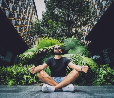 Genç adam ormanda güzel yeşil yapraklarla yoga yapıyor..