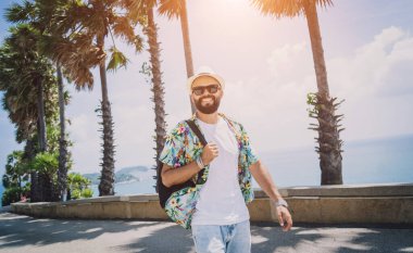 Yaz tatilinde arka planda güzel palmiyeler ve deniz manzaraları olan genç bir gezgin..