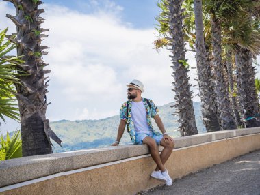 Yaz tatilinde arka planda güzel palmiyeler ve deniz manzaraları olan genç bir gezgin..