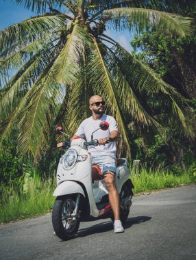 Şık bir genç adam ve motosikleti ormanda yolda..