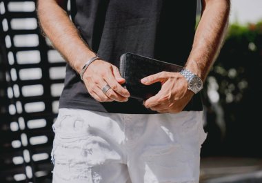 Genç işadamı cüzdanını modern evine karşı elinde tutuyor. Garajı ve arabası var..