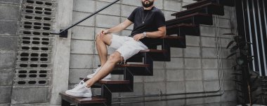 Şehrin sokaklarındaki merdivenlerde tişörtlü ve şortlu genç bir adam..