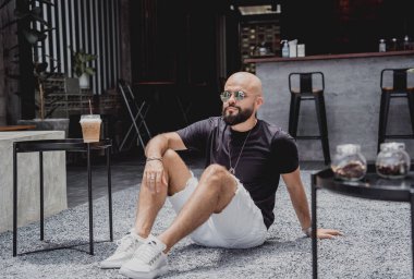 Modern şehir kafesinde tişört ve şort giyen genç bir adam..