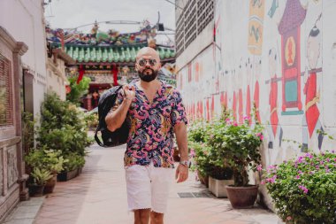 Asya tapınağının arka planında sırt çantası olan genç bir adam..