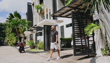 Genç işadamı garajı ve arabasıyla modern evinden çıkıyor..