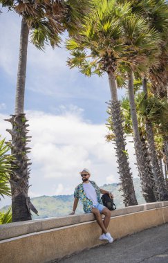 Yaz tatilinde arka planda güzel palmiyeler ve deniz manzaraları olan genç bir gezgin..