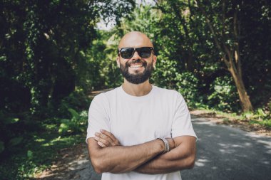 Şık bir genç adam ve motosikleti ormanda yolda..