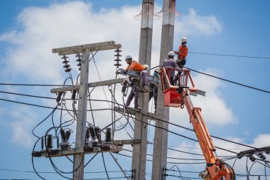 Electricians is repairing high voltage wires on electric power pole.