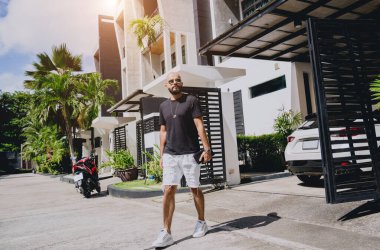 Genç işadamı garajı ve arabasıyla modern evinden çıkıyor..