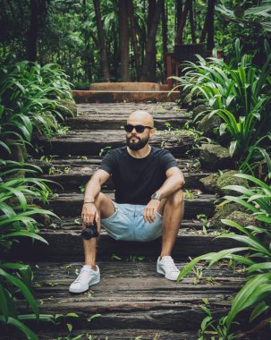 Ormanda yeşil yaprakları olan genç bir adamın portresi..