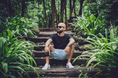 Ormanda yeşil yaprakları olan genç bir adamın portresi..