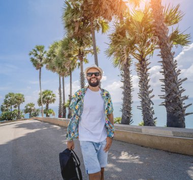 Yaz tatilinde arka planda güzel palmiyeler ve deniz manzaraları olan genç bir gezgin..