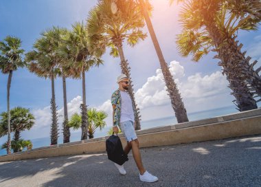 Yaz tatilinde arka planda güzel palmiyeler ve deniz manzaraları olan genç bir gezgin..