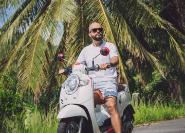 Şık bir genç adam ve motosikleti ormanda yolda..