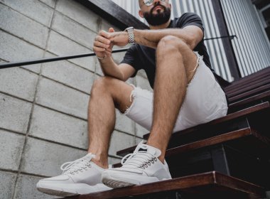 Şehrin sokaklarındaki merdivenlerde tişörtlü ve şortlu genç bir adam..