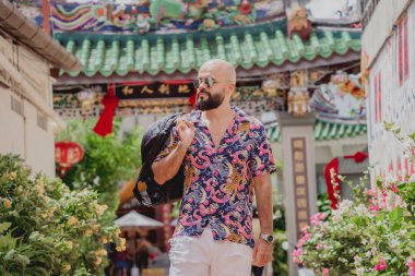 Asya tapınağının arka planında sırt çantası olan genç bir adam..