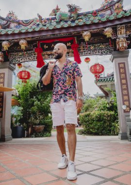 Asya tapınağının arka planında sırt çantası olan genç bir adam..