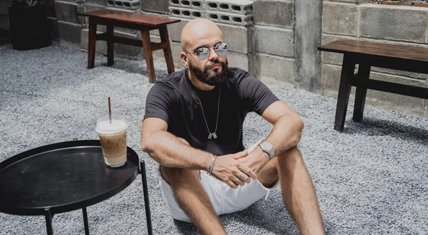 Modern şehir kafesinde tişört ve şort giyen genç bir adam..