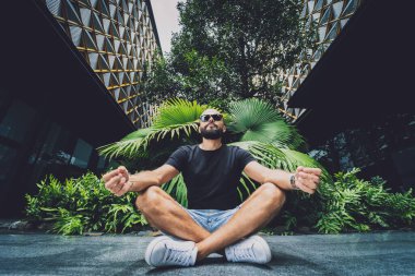 Genç adam ormanda güzel yeşil yapraklarla yoga yapıyor..