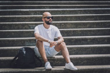 Yalnız genç yakışıklı adam parkta merdivenlerde oturuyor..