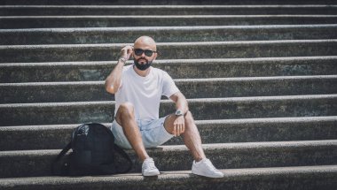 Yalnız genç yakışıklı adam parkta merdivenlerde oturuyor..