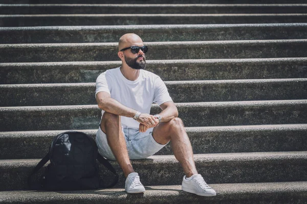 Yalnız genç yakışıklı adam parkta merdivenlerde oturuyor..