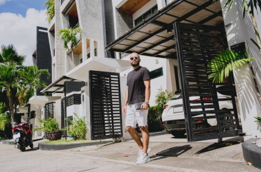 Genç işadamı garajı ve arabasıyla modern evinden çıkıyor..