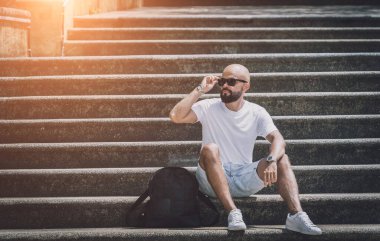 Yalnız genç yakışıklı adam parkta merdivenlerde oturuyor..