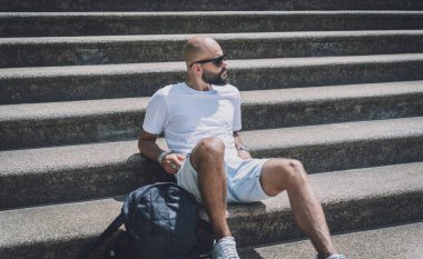 Yalnız genç yakışıklı adam parkta merdivenlerde oturuyor..