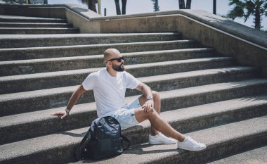 Yalnız genç yakışıklı adam parkta merdivenlerde oturuyor..