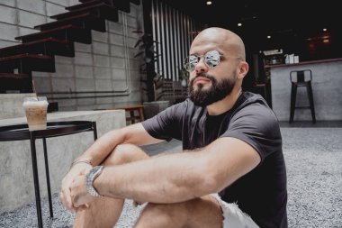 Modern şehir kafesinde tişört ve şort giyen genç bir adam..