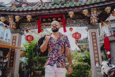 Asya tapınağının arka planında sırt çantası olan genç bir adam..