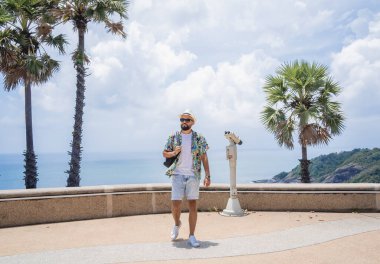 Arka planda dürbünlü teleskopla yürüyen bir adam.