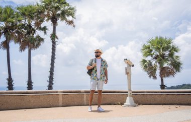 Arka planda dürbünlü teleskopla yürüyen bir adam.