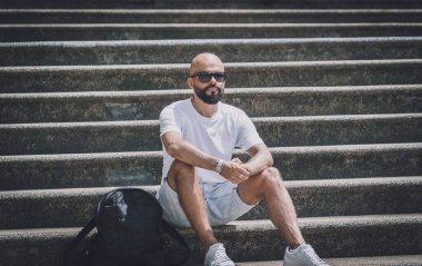 Yalnız genç yakışıklı adam parkta merdivenlerde oturuyor..