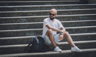Yalnız genç yakışıklı adam parkta merdivenlerde oturuyor..