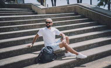 Yalnız genç yakışıklı adam parkta merdivenlerde oturuyor..