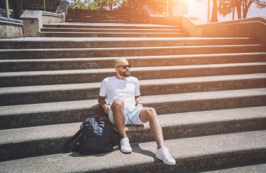 Yalnız genç yakışıklı adam parkta merdivenlerde oturuyor..